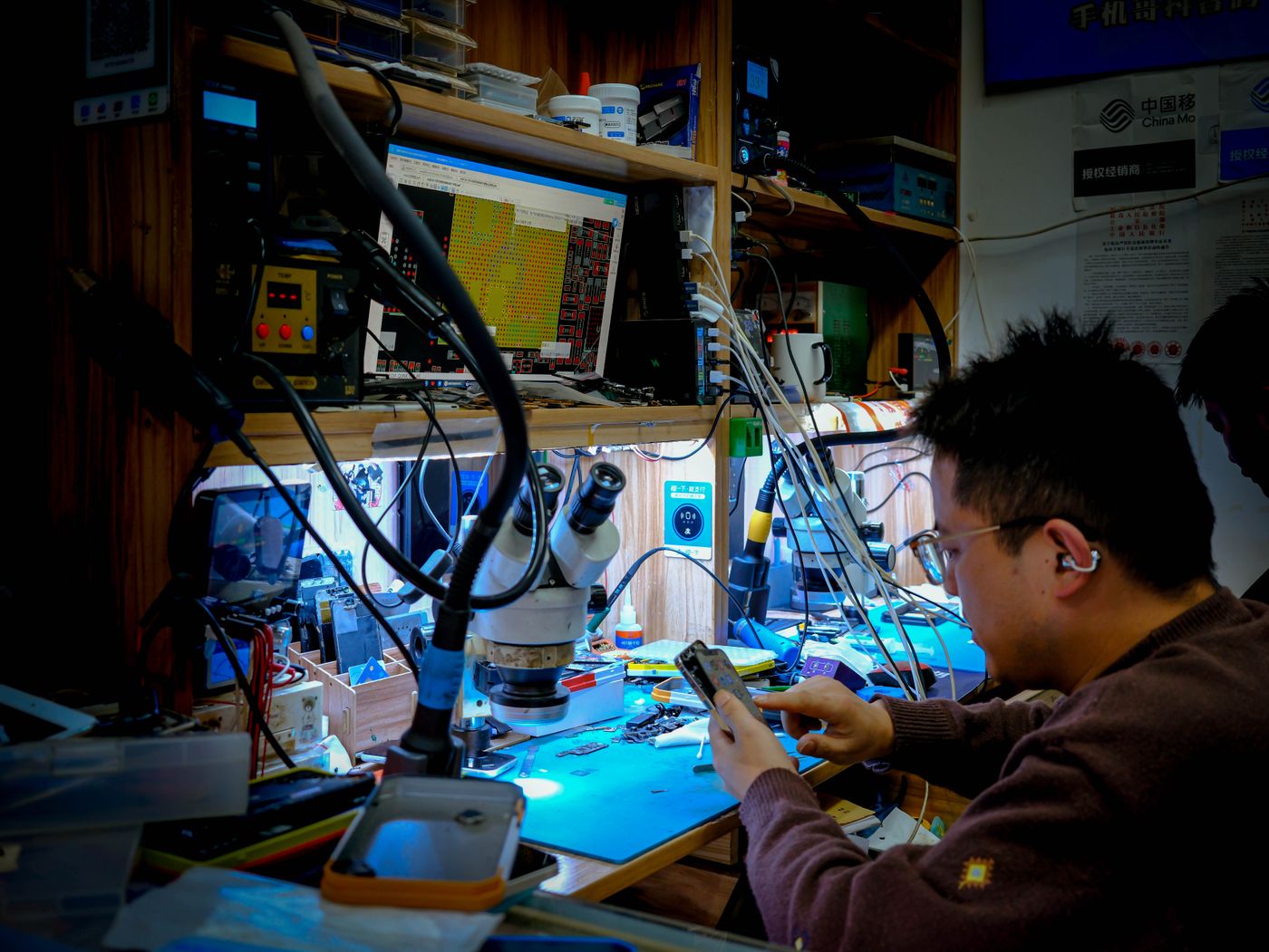 Technician carrying out detailed television circuit board repairs